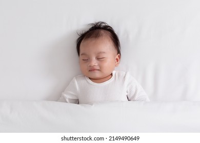 Happy Asian Newborn Baby Lying Sleeps On A White Bed Comfortable And Safety.Cute Asian Newborn Sleeping And Napping At Warmth Place Deep Sleep And Fresh Breathing.Newborn Baby Sleep Concept.Top View