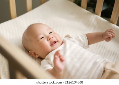 Happy Asian Newborn Baby Smiling And Laughing In Crib