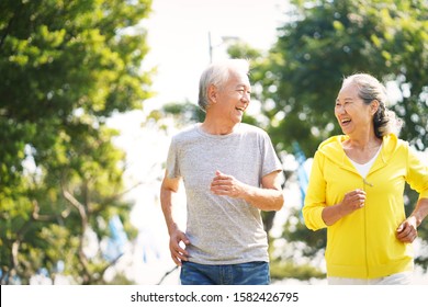 happy asian old couple jogging running outdoors in park - Shutterstock ID 1582426795