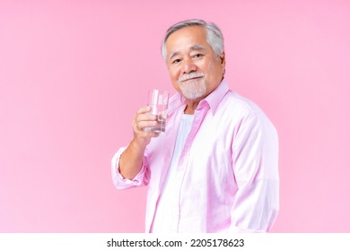 Happy Asian Old Man Hand Holding Glass Of Water Drinking Smile Wearing Pink Shirt And Pink Black Background.