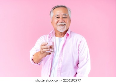 Happy Asian Old Man Hand Holding Glass Of Water Drinking Smile Wearing Pink Shirt And Pink Black Background.