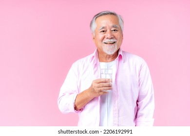 Happy Asian Old Man Hand Holding Glass Of Water Drinking Smile Wearing Pink Shirt And Pink Black Background.