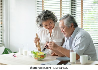 Happy Asian Older couple relaxing preparing and cooking healthy salad at home together. Romantic Senior man and woman smiling enjoying a meal. 