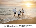 Happy Asian parents and daughters have delightful time on beach. Little girls bond with their mother and father running jumping and pretending to fly with arms wide open. Family fun under sun.