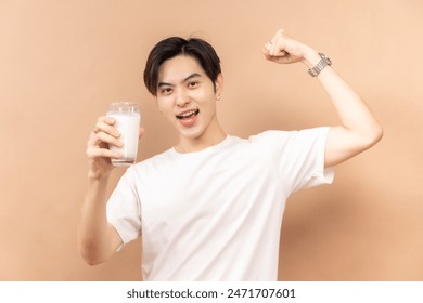 A happy asian people in white shirts, holding glasses of milk and a bowl of salad, against a beige background. - Powered by Shutterstock