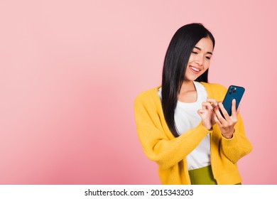 Happy Asian Portrait Beautiful Cute Young Woman Teen Smiling Excited Typing Text Message On Smart Mobile Phone Enjoys Online Communication Isolated, Studio Shot On Pink Background With Copy Space