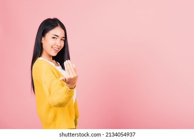 Happy Asian portrait beautiful cute young woman teen smile positive friendly making gesture hand inviting to come here with hand look to camera studio shot isolated on pink background with copy space