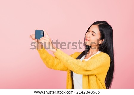 Happy Asian portrait beautiful cute young woman smiling excited  making selfie photo, video call on smartphone studio shot isolated on pink background with copy space