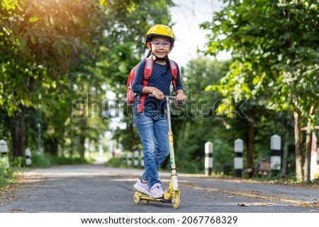 Happy Asian school girl ride a scooter to school idea concept