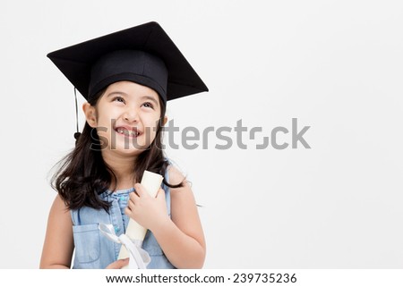 Happy Asian school kid graduate in graduation cap looking up