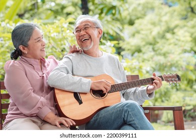 Happy Asian senior couple elderly man playing guitar music song enjoy having fun happiness outside house near backyard garden. Retirement insurance concept - Powered by Shutterstock