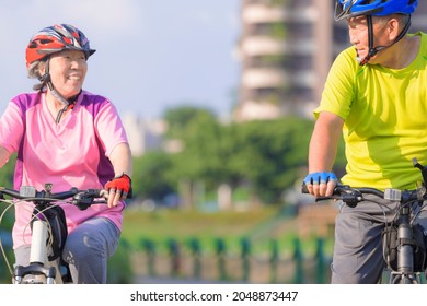 Happy  Asian Senior Couple Exercising With Bicycles In The City Park