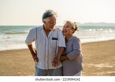 Happy Asian senior couple family travel on summer beach vacation. Healthy elderly retired man and woman relax and enjoy outdoor lifestyle embracing and walking together on the beach at summer sunset. - Powered by Shutterstock