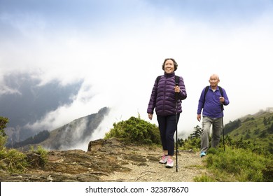 Happy Asian Senior Couple Hiking On The Mountain