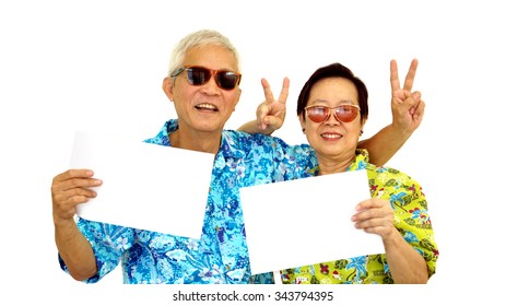 Happy Asian Senior Couple Holding White Blank Sign Ready For Holiday Trip