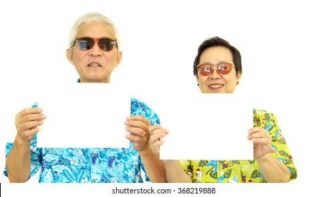 Happy Asian Senior Couple Holding White Blank Sign Ready For Holiday Trip