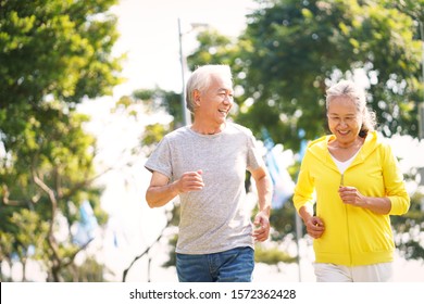 happy asian senior couple running exercising outdoors in park