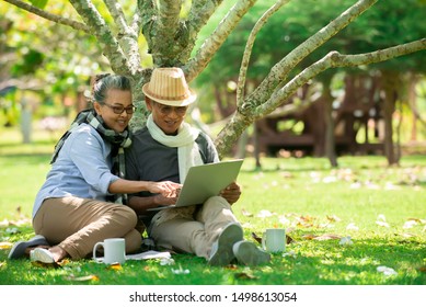 Happy  Asian Senior Couple Sitting At Park While Using Laptop Computer, Retirement Planning Family Lifestyle Healthy  Travel Vacation Concept