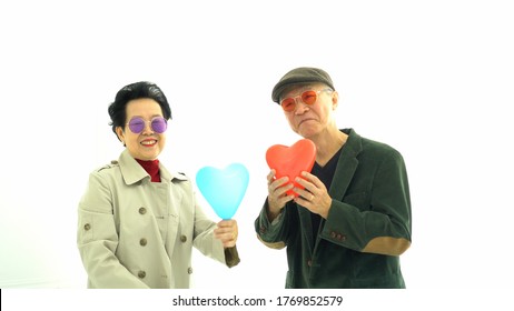 Happy Asian Senior Elder Couple In Winter Fashion Exchange And Play Heart Balloons