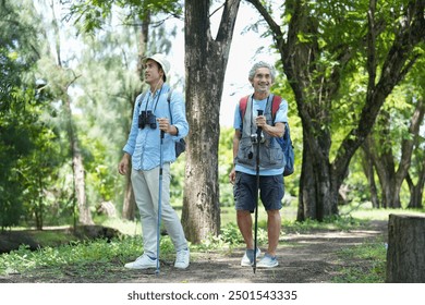 happy asian senior father and mature adult son spend holiday time walking with trekking poles in the forest park,exploring,travel close up in nature