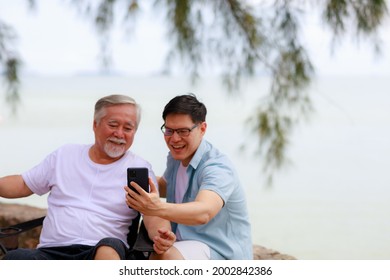 Happy Asian Senior Father Using Smartphone With His Son