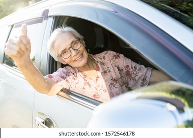 Happy Asian Senior Female Driver With A Smiling In Her Car, Enjoying Traveling During Retirement Age,healthy Old People Feel Fun,elderly Woman Driving Car, Giving A Thumbs Up, Road Trip,travel Concept