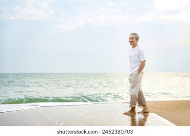 happy asian senior man barefoot walking on sand beach in the morning,healthy elderly male relaxing in nature,wellness,wellbeing - Powered by Shutterstock