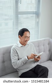 Happy Asian Senior Man Using The Mobile Phone At Home