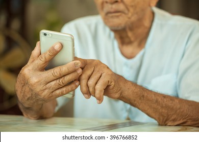 Happy Asian Senior Man Using The Mobile Phone At Home