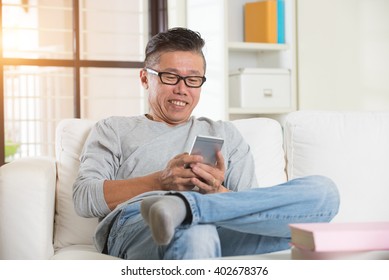 Happy Asian Senior Man Using The Mobile Phone At Home

