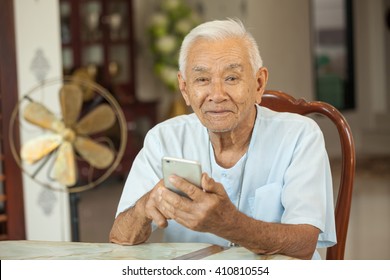 Happy Asian Senior Man Using The Mobile Phone At Home