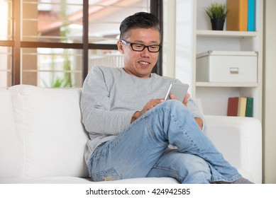 Happy Asian Senior Man Using The Mobile Phone At Home

