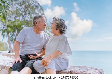 Happy asian senior retired couple, relax smiling elder man and woman enjoying with retired vacation at sea beach outdoor. Health care, Family outdoor lifestyle