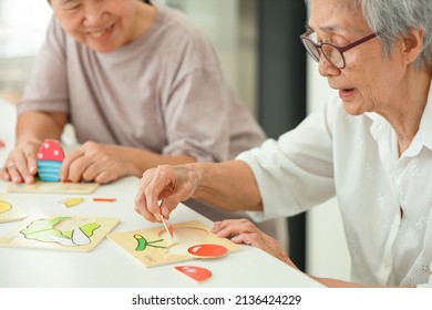 Happy Asian Senior Woman Holding Picture Puzzle Pieces,old Elderly Playing A Jigsaw Puzzle At Home,training Memory And Brain Development,practice Hands Or Fingers Muscle Exercise In Picking Up Objects