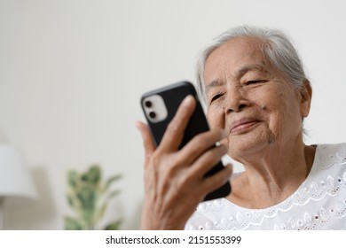 Happy Asian Senior Woman Using  Smartphone At Home. Grandparent Call To Family Member Using Mobile Phone Application.