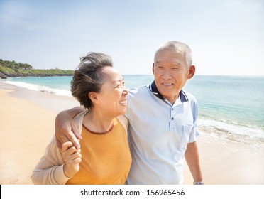 Happy Asian Seniors Walking On The Beach