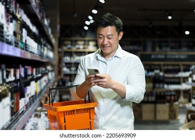 Happy Asian Shopper In Supermarket Using Smartphone App To Select And Scan Wine