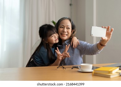 Happy Asian Smiling Older Grandma And Child Girl Having Fun Taking Selfie On Phone, Cheerful Granny With Little Kid Play Making Photo On Mobile