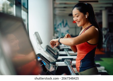 Happy Asian sportswoman using smart watch while jogging on treadmill during sports training in a gym. - Powered by Shutterstock