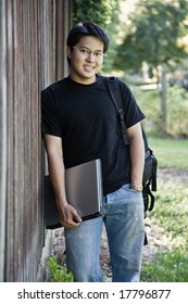 A Happy Asian Student Carrying A Laptop And A Backpack