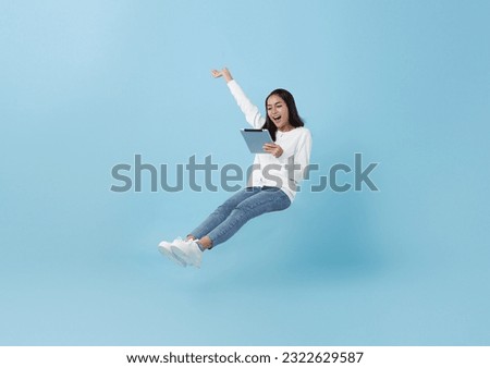 Happy asian teenage girl using tablet social media online floating in mid-air isolated on blue background. freedom fast internet technology concept.