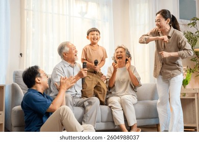 Happy Asian three generation family have fun singing and dancing together in living room. Big family grandparent and grandchild enjoy weekend activities lifestyle relaxing and playing together at home