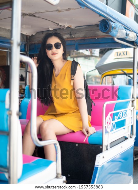 Happy\
Asian tourist sitting on Tuk Tuk taxi in\
Thailand.
