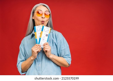 Happy Asian Traveler Tourist Elderly Mature Senior Woman Holding Tickets Isolated On Red Background Studio. Passenger Travel Abroad On Weekends. 