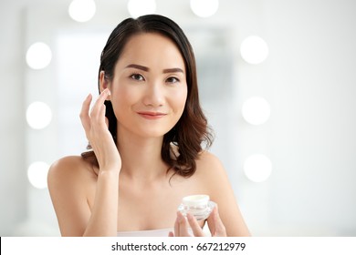 Happy Asian Woman Applying Eye Cream