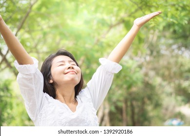 Happy Asian Woman Arms Up And Breathing Deep Outdoors With Nature Background 