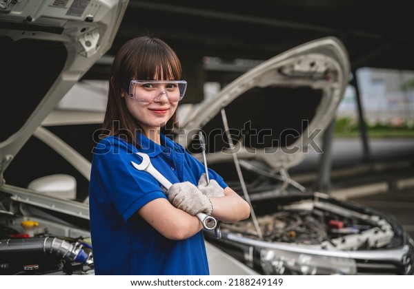 Happy Asian woman auto mechanic in garage.
Professional auto mechanic who inspects and repairs engine in
garage. Car repair and maintenance
concept.