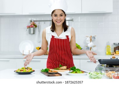 Happy Asian woman chef with red apron standing in the kitchen. Concept woman cooking at home. - Powered by Shutterstock