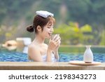 Happy asian woman drinking sake in the hotspring smilling