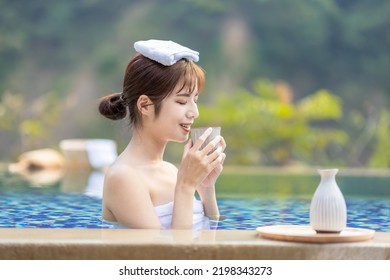 Happy asian woman drinking sake in the hotspring smilling